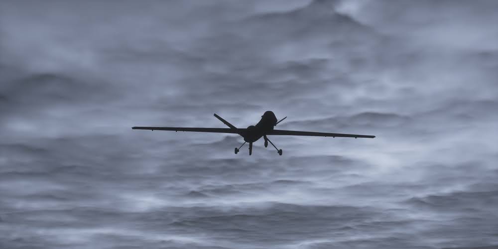 silhouette of a military uav against a dark, cloudy sky